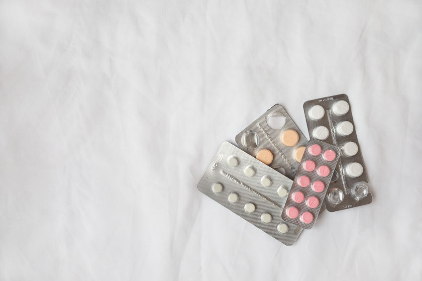 Variety of pills in silver blisters lie on white crumpled bed sh Variety of pills in silver blisters lie on white crumpled bed sh
